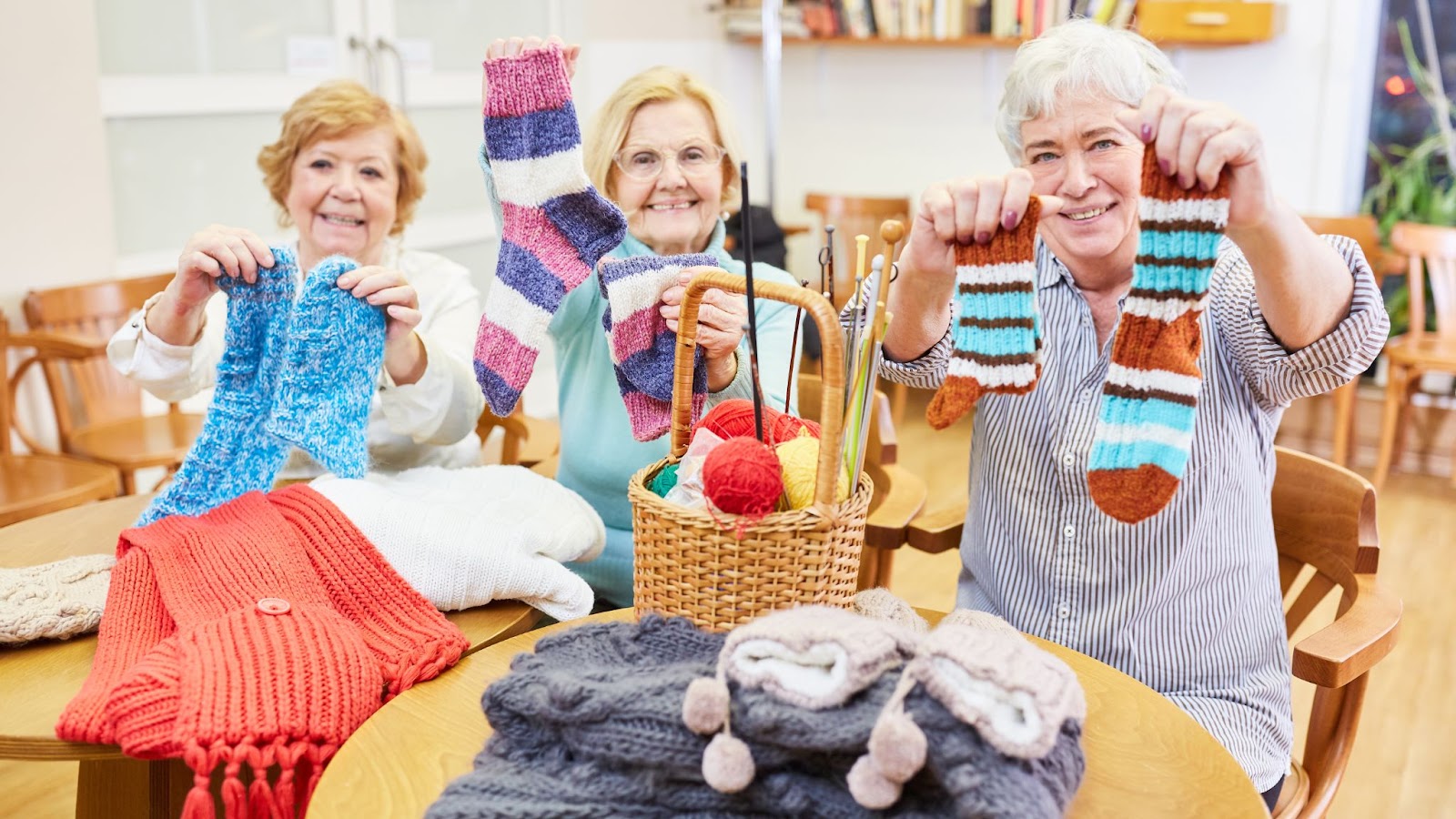 A group of happy seniors displaying their beautiful knitting projects.