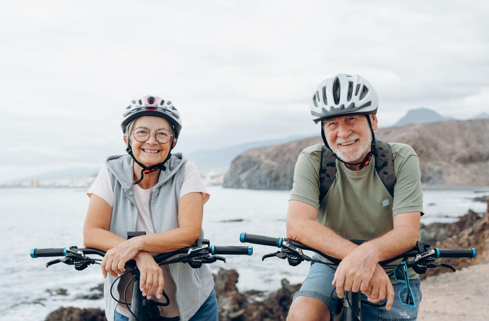 A happy senior couple embracing aging by staying active and enjoying a bike ride together.