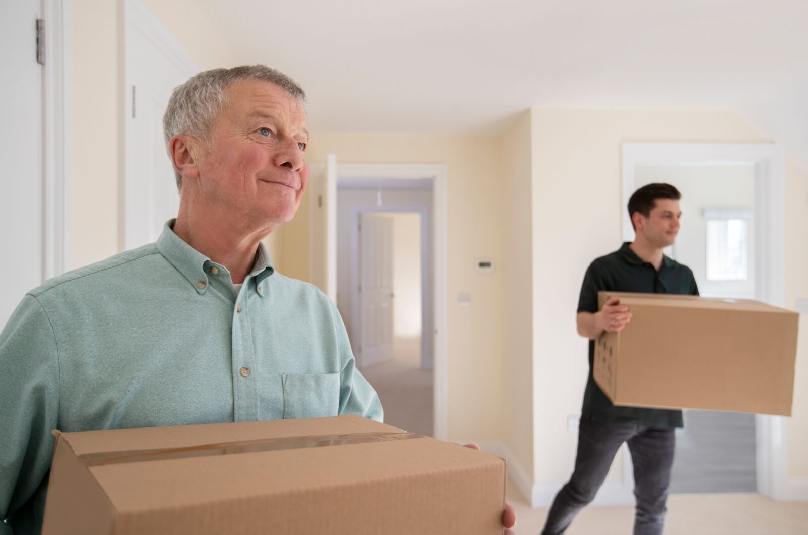 An adult child and their parent holding boxes while downsizing.