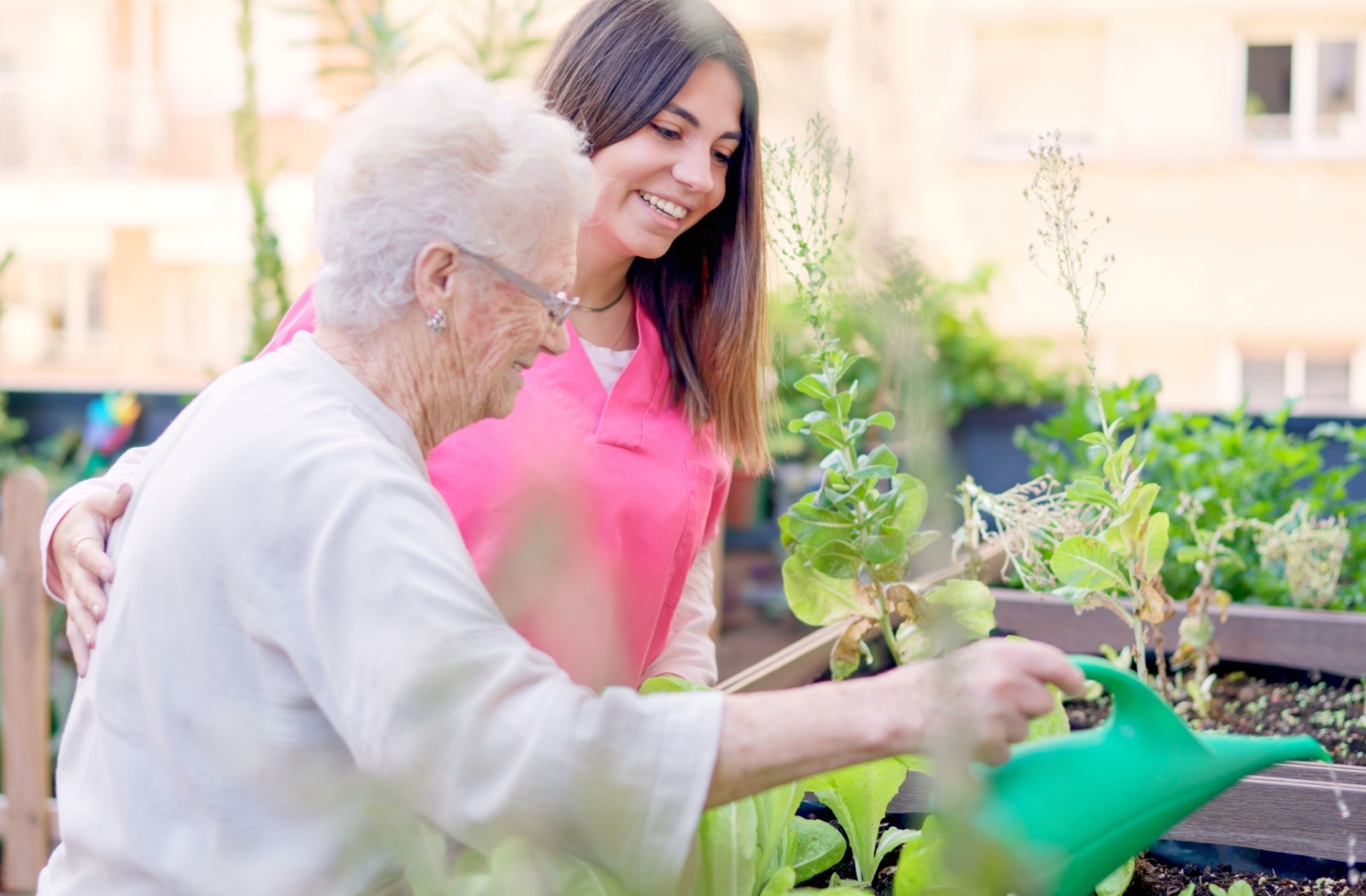 A patient caregiver helps a senior work in the community garden as a means of staying cognitively engaged.
