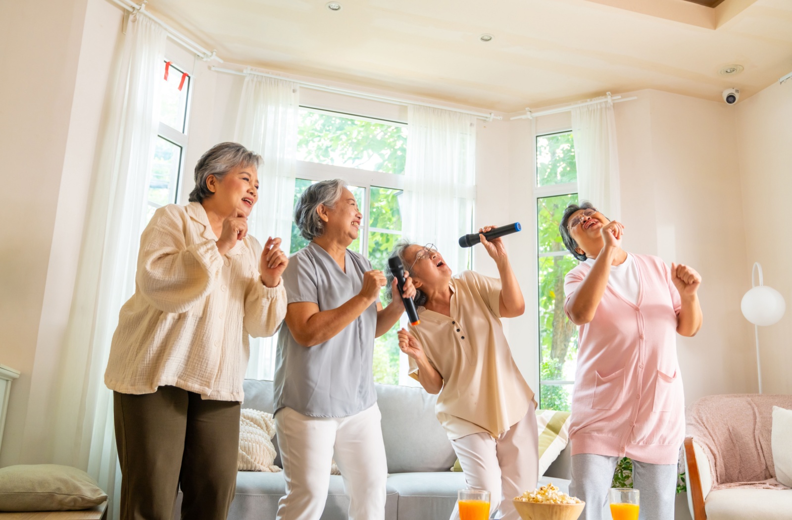 A group of seniors having fun singing karaoke in their assisted living community.