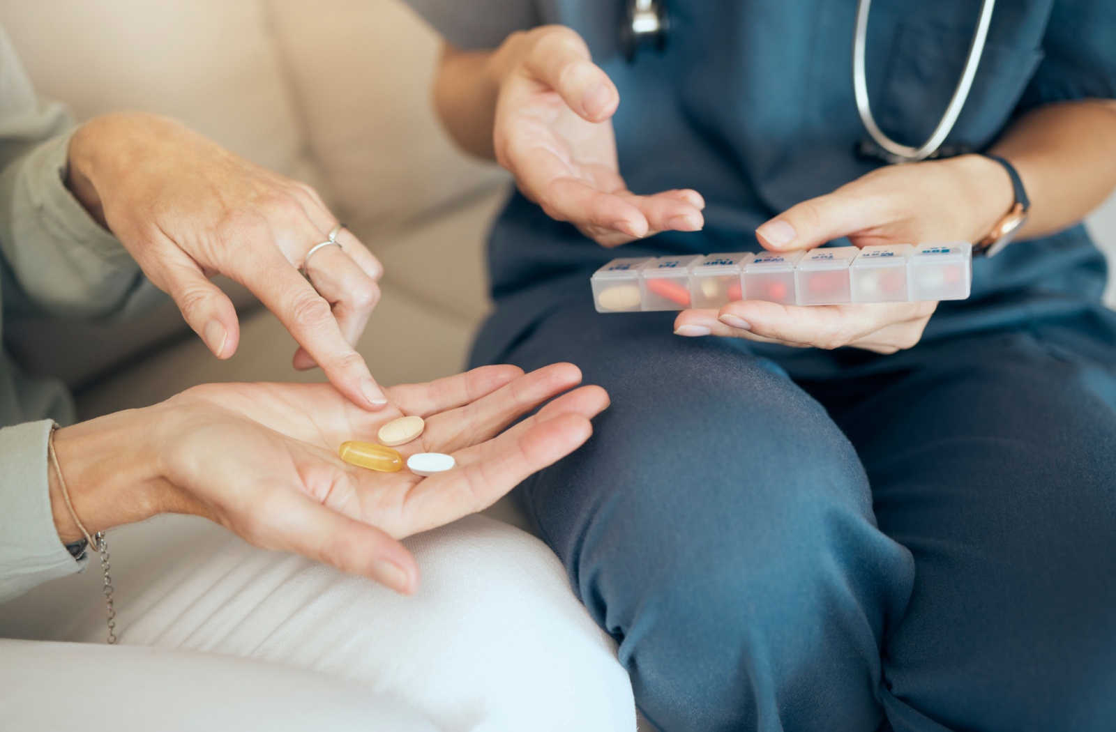 A close-up image of a professional assisted living caregiver helping a senior resident with medication management.
